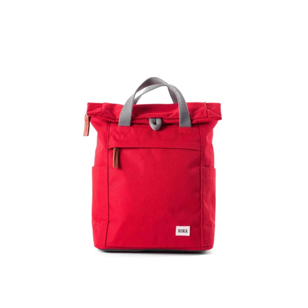 Red roll-top backpack with gray handles and a small front pocket. The brand "ROKA" is subtly displayed on the bottom.