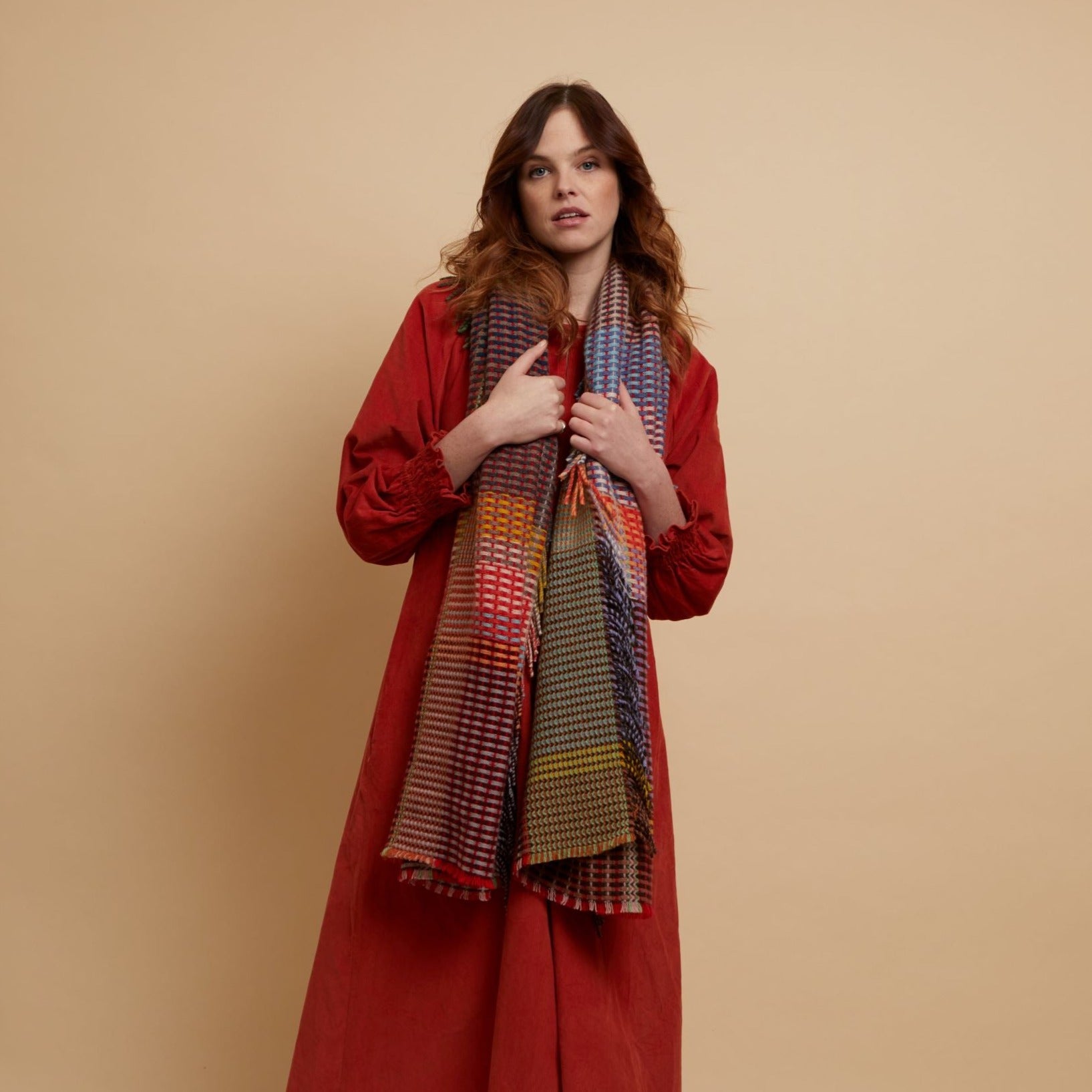 Multicolored woven wool scarf with red, blue, green, and beige sections;  fringed edges.