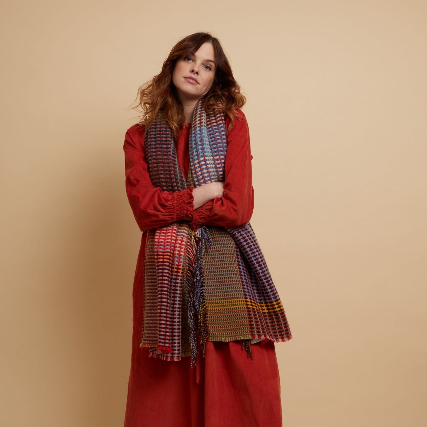 Multicolored woven wool scarf with red, purple, blue, and beige checkered pattern and fringed edges.