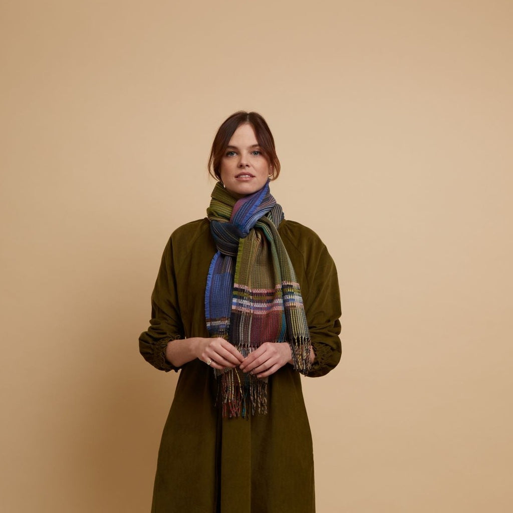 Multicolored woven scarf with fringed edges, featuring shades of blue, green, and purple in a plaid pattern.