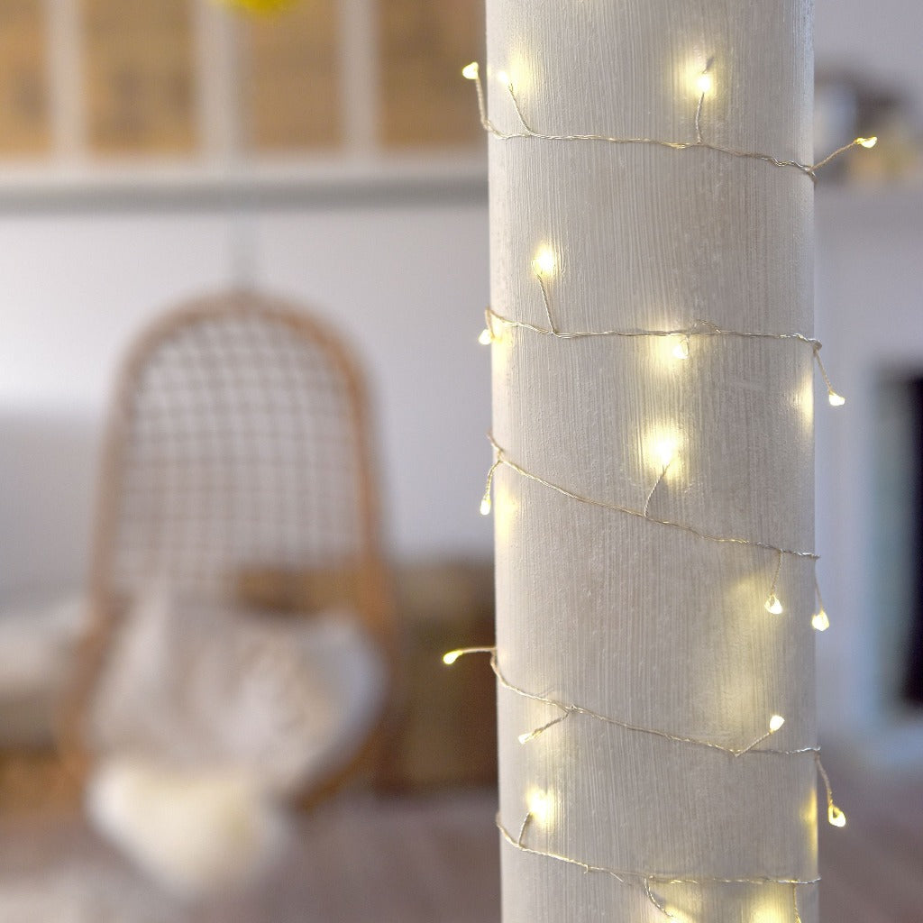 Warm-white LED string lights wrapped around a white pillar.