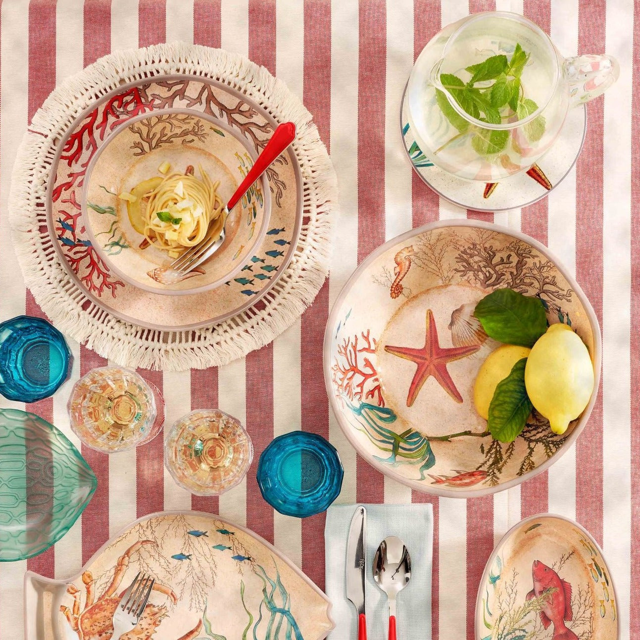 Set of nautical-themed dinnerware featuring bowls and plates decorated with coral, starfish, and fish illustrations.