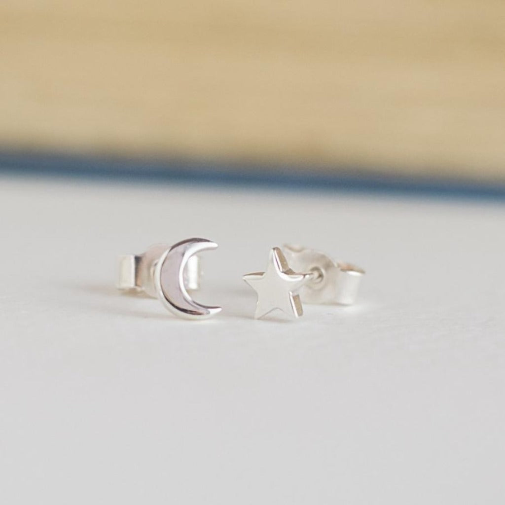 Silver crescent moon and star stud earrings.  The moon features a pale pink interior.