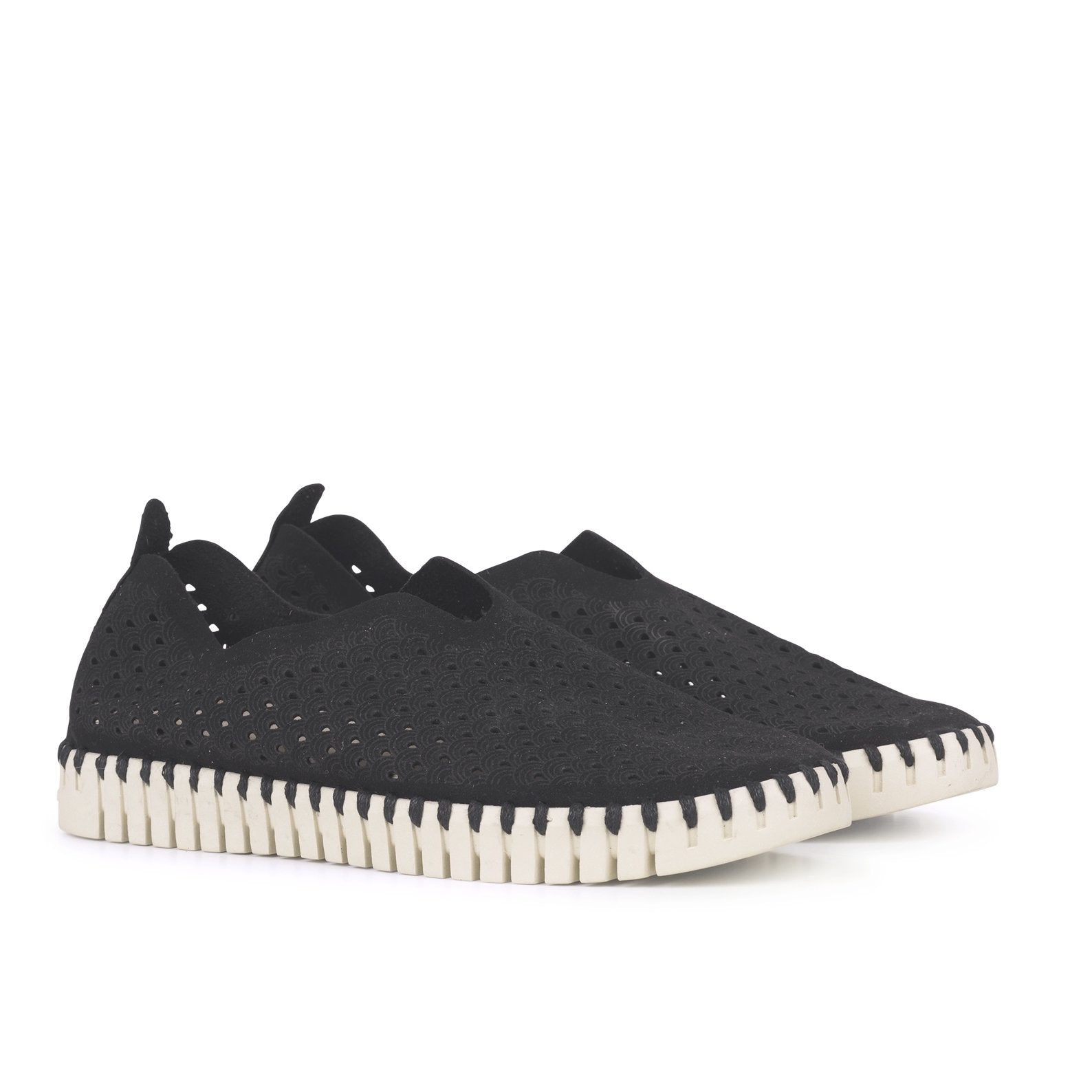 Pair of black slip-on shoes with perforated pattern and cream-colored sole.