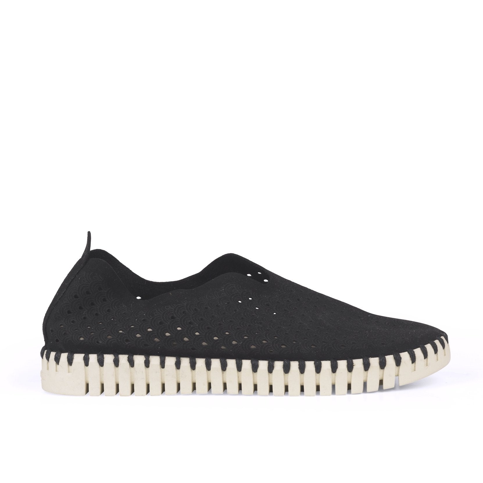 Black slip-on shoe with perforated pattern and cream-colored, textured sole.