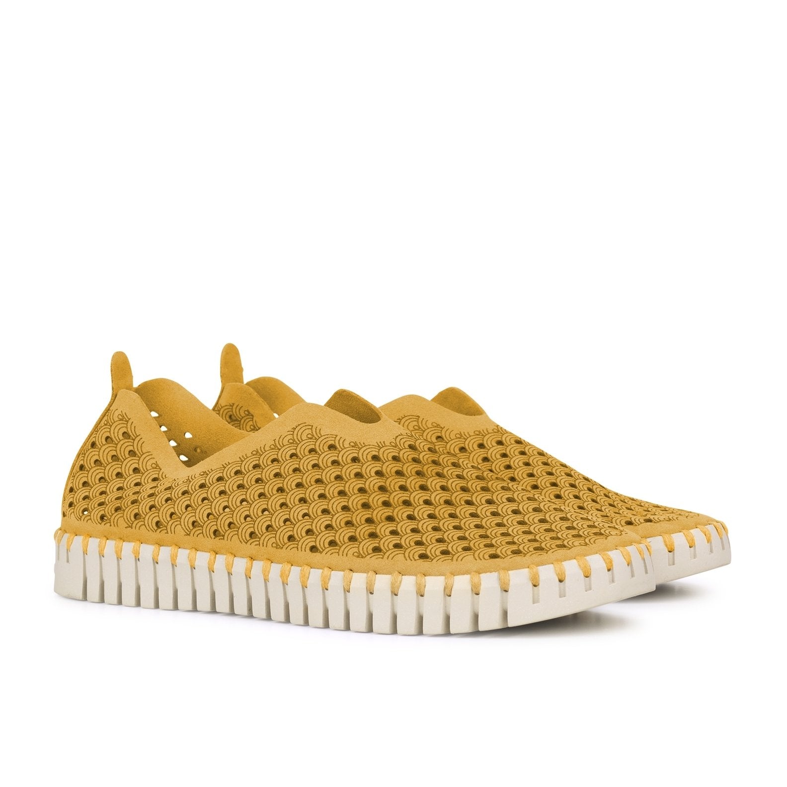 Mustard yellow slip-on shoes with a textured, patterned upper and a white, ridged sole. The pattern is a repeating wave design.