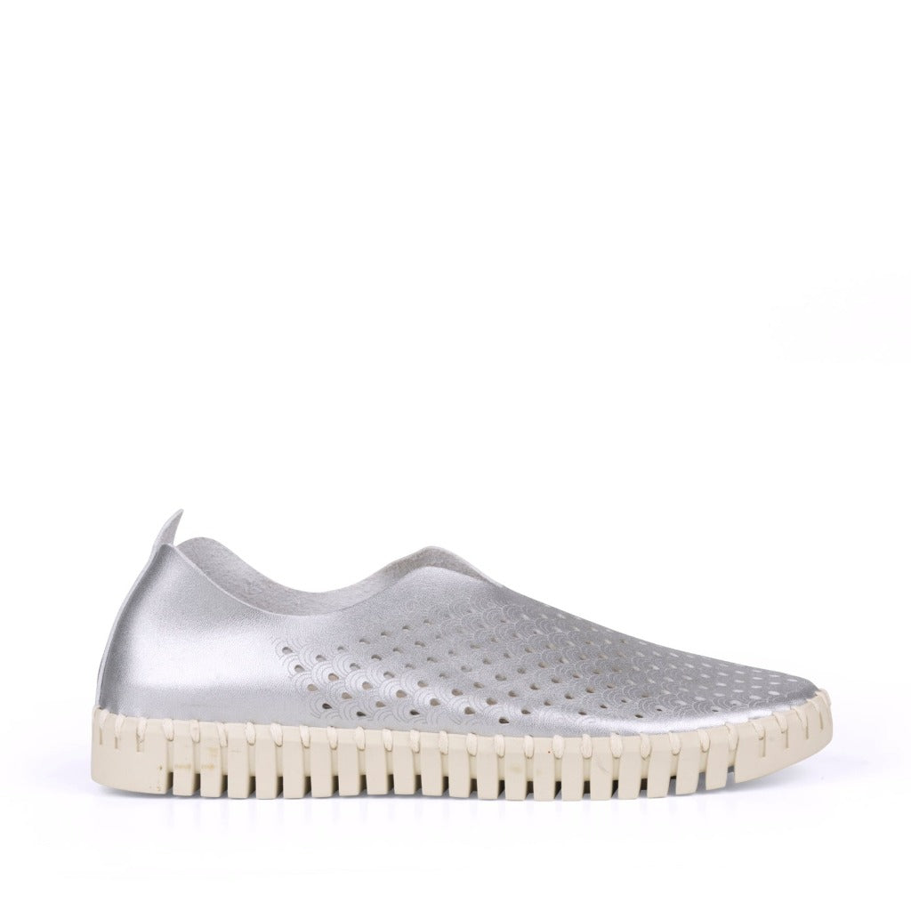 Silver slip-on shoe with perforated detailing and a cream-colored, textured sole.