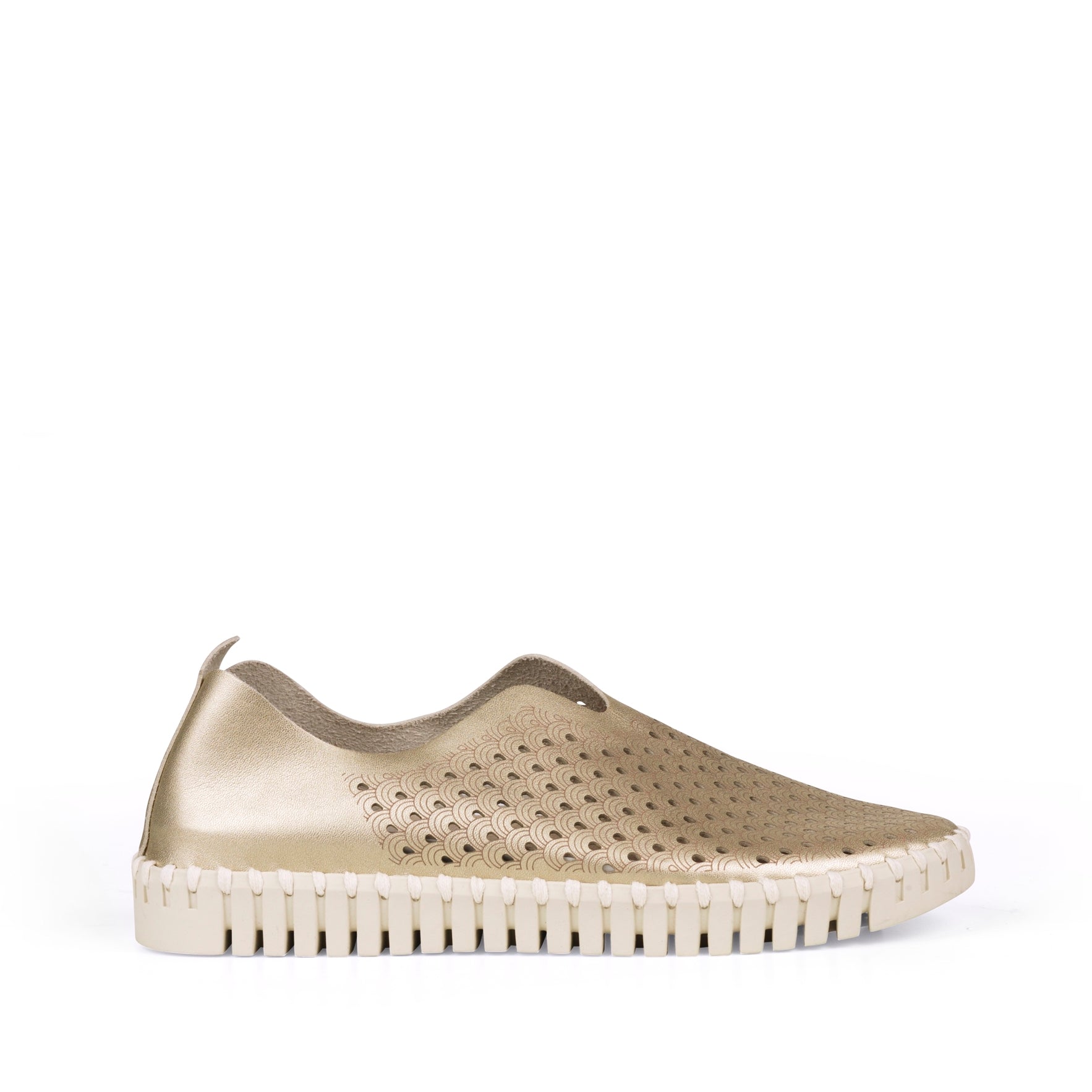 Gold leather slip-on shoe with cream sole and patterned cutouts. The shoe features a textured, scalloped sole and delicate