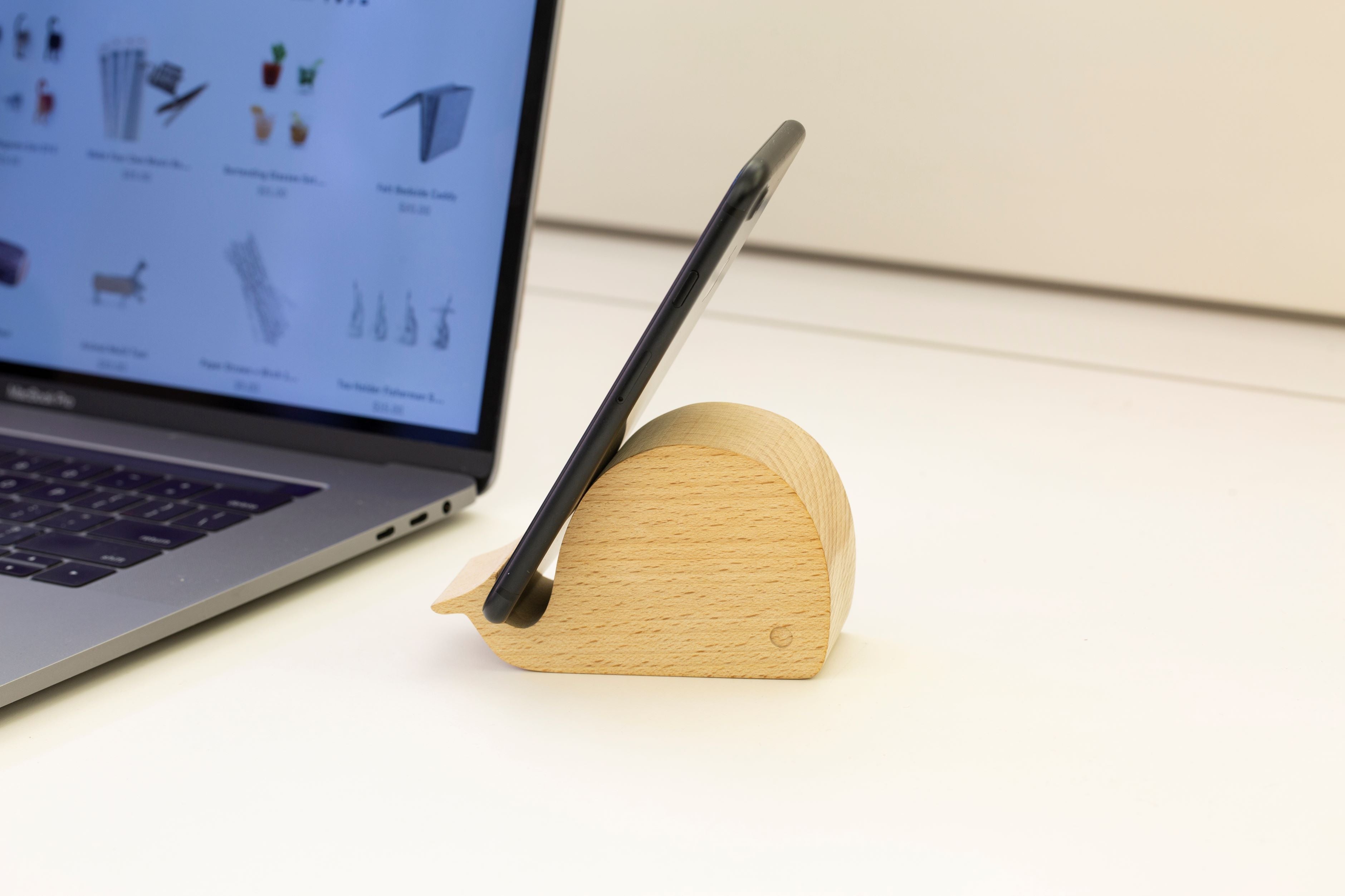 Wooden whale-shaped smartphone stand holding a black smartphone.