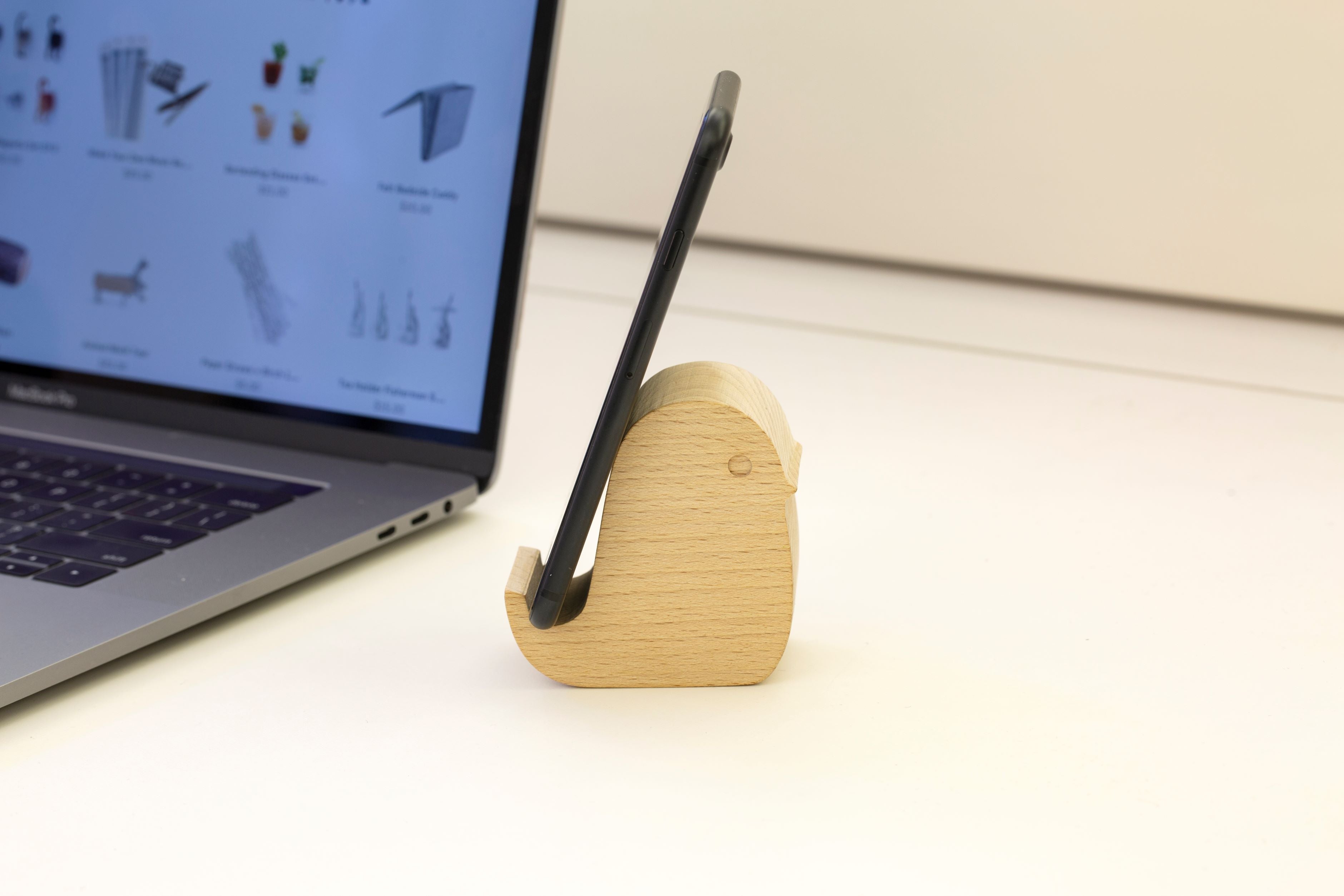 Wooden bird-shaped smartphone stand holding a black smartphone.