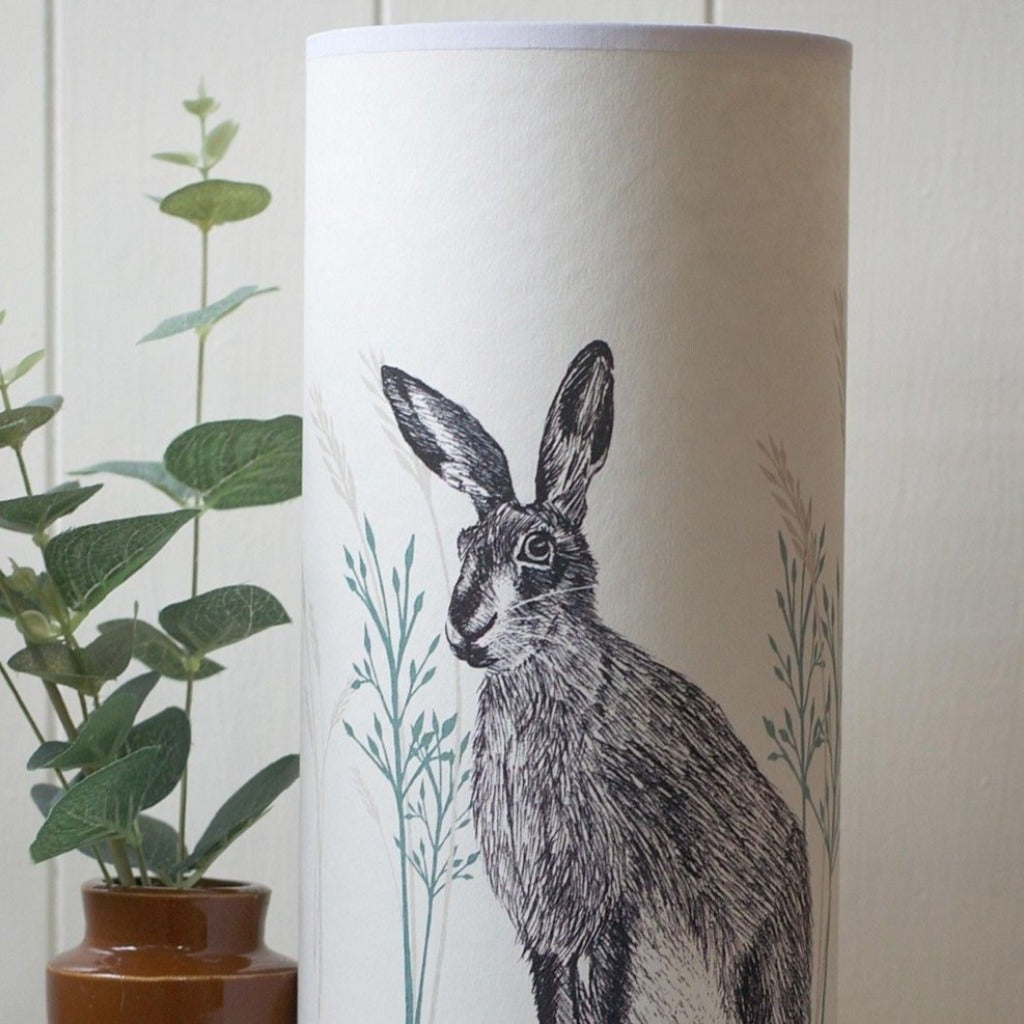 Cream cylindrical lampshade featuring a black and grey ink drawing of a hare amidst stylized grasses.