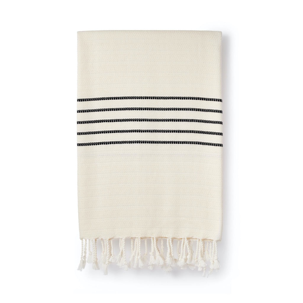 Off-white Turkish towel with three thin black stripes and a fringed bottom.