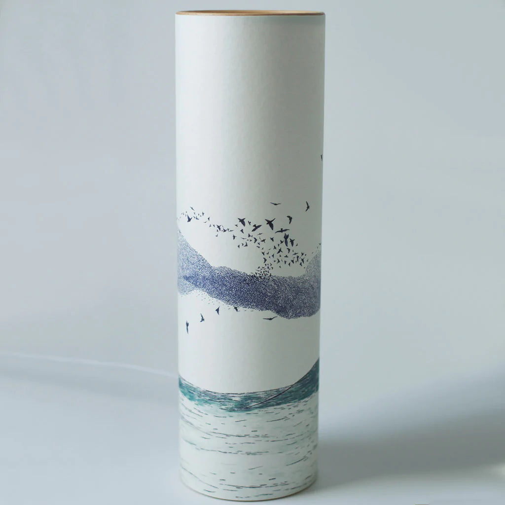Tall cylindrical container with a wood top, featuring a minimalist design of birds in flight over a stylized landscape and
