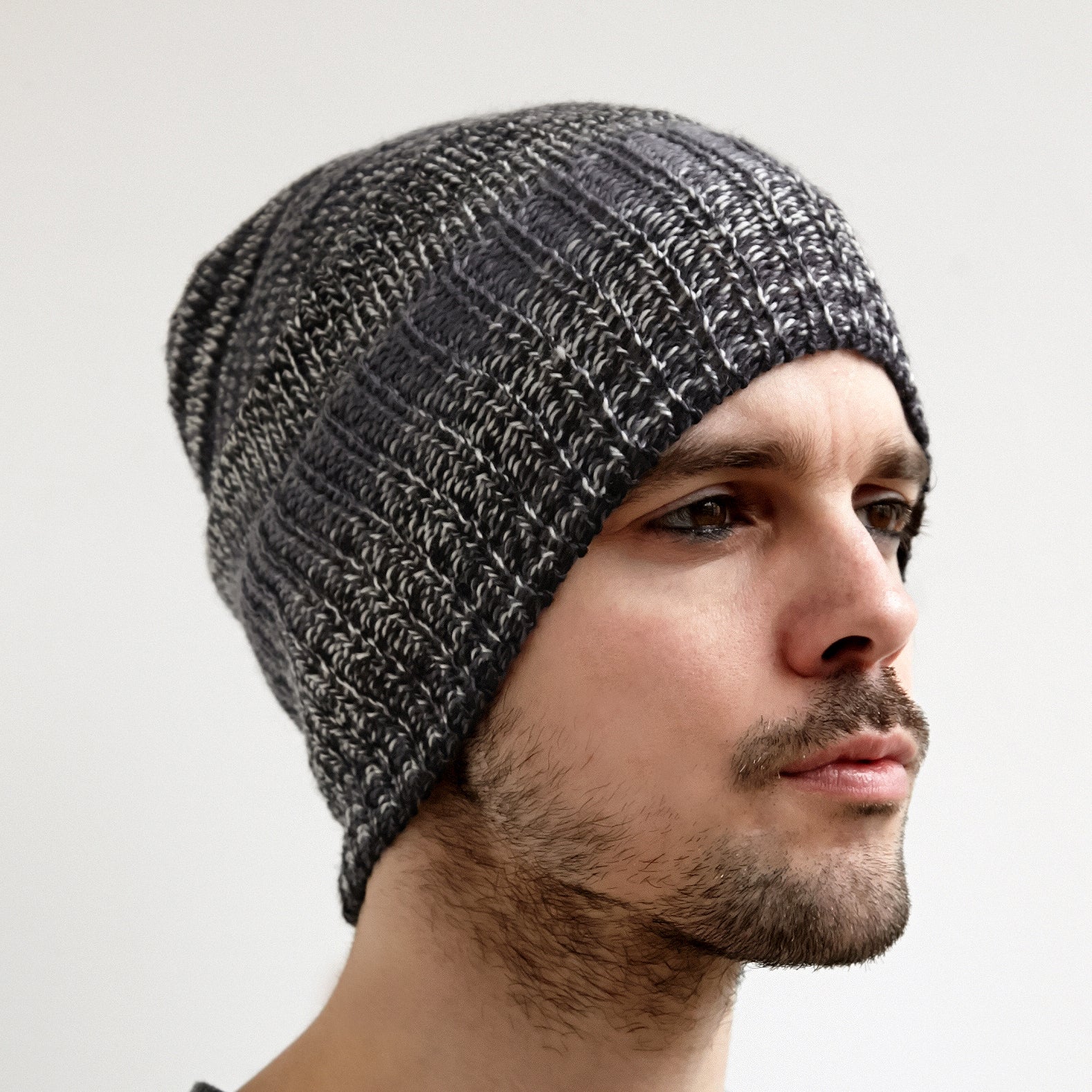Close-up of a gray and black knit beanie. The hat has a ribbed texture and a slouchy fit.