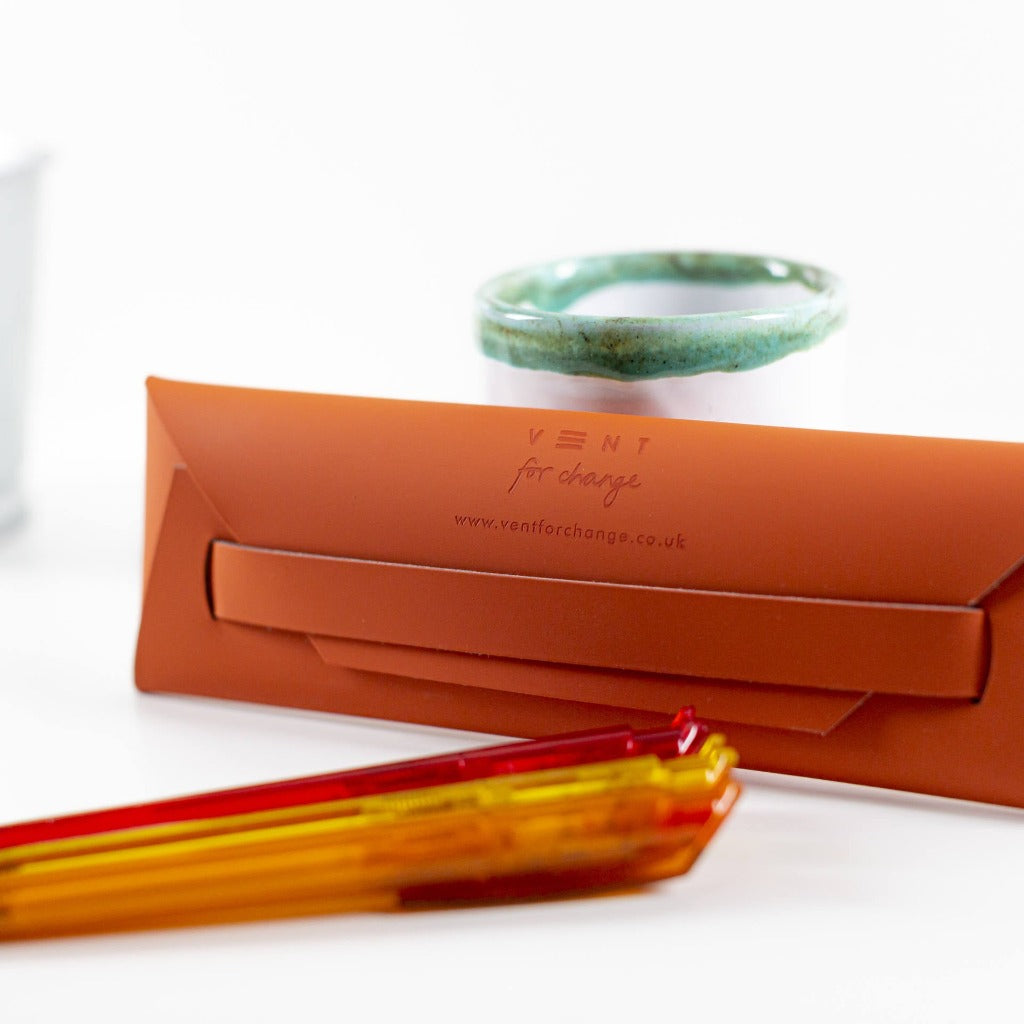 Burnt orange leather eyewear case with "VENT for change" and website address embossed.