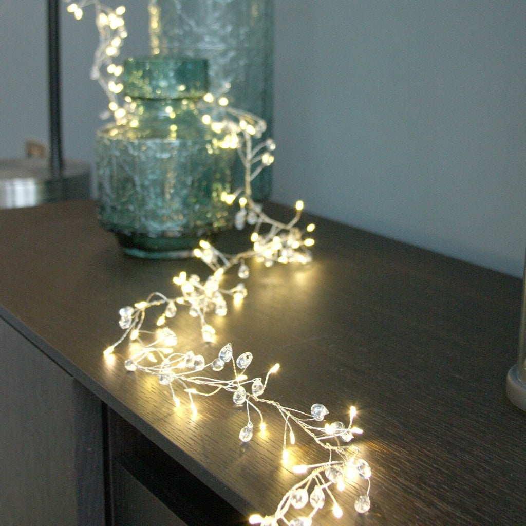 LED fairy lights with clear crystal beads, draped on a dark surface.