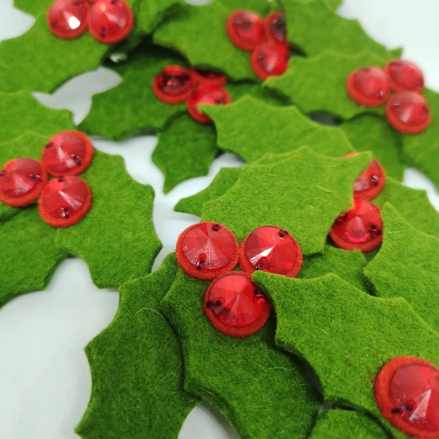 Green felt holly leaves adorned with red jeweled berries.
