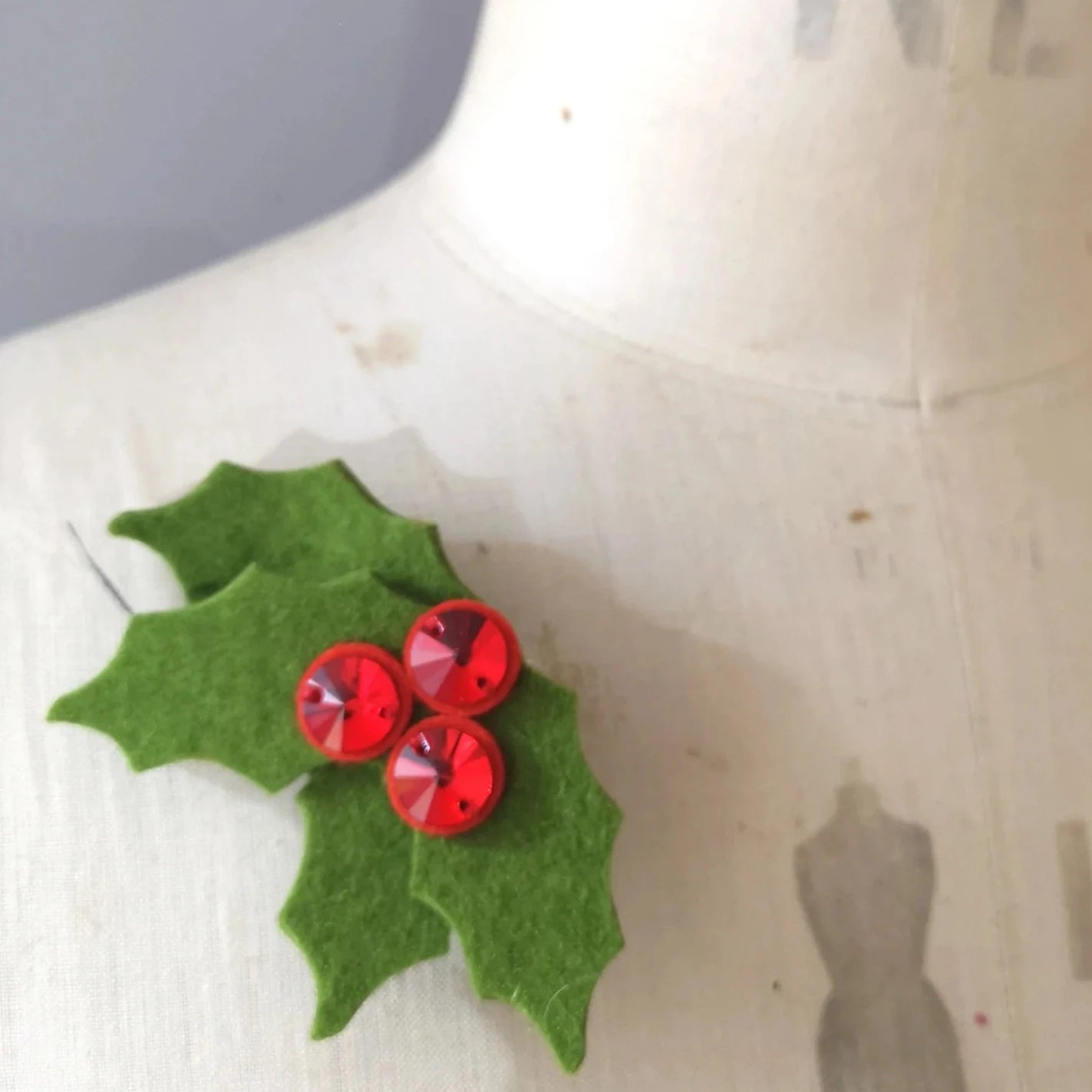 Green felt holly leaf brooch with three red rhinestone berries.