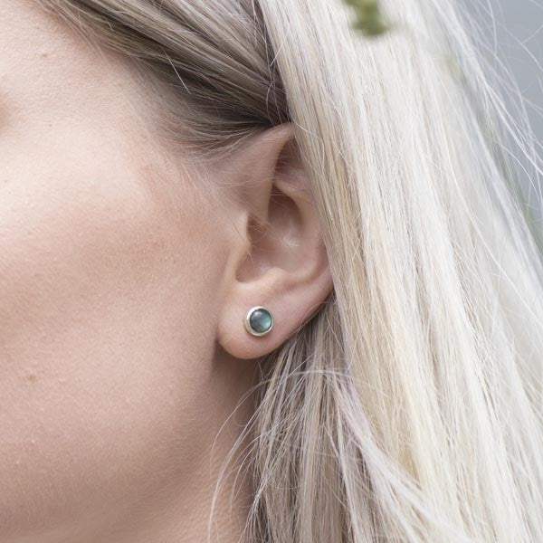 Silver stud earrings featuring round, dark gray gemstones.