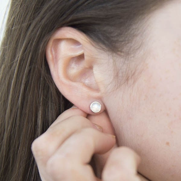 Pair of small, round, white gemstone stud earrings in silver settings.