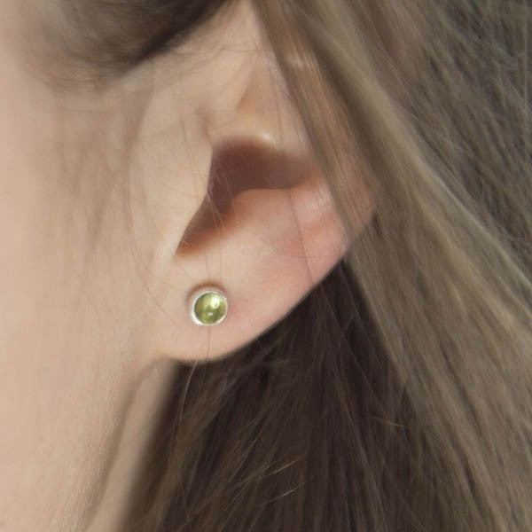 Silver stud earrings featuring small, round, olive-green gemstones.