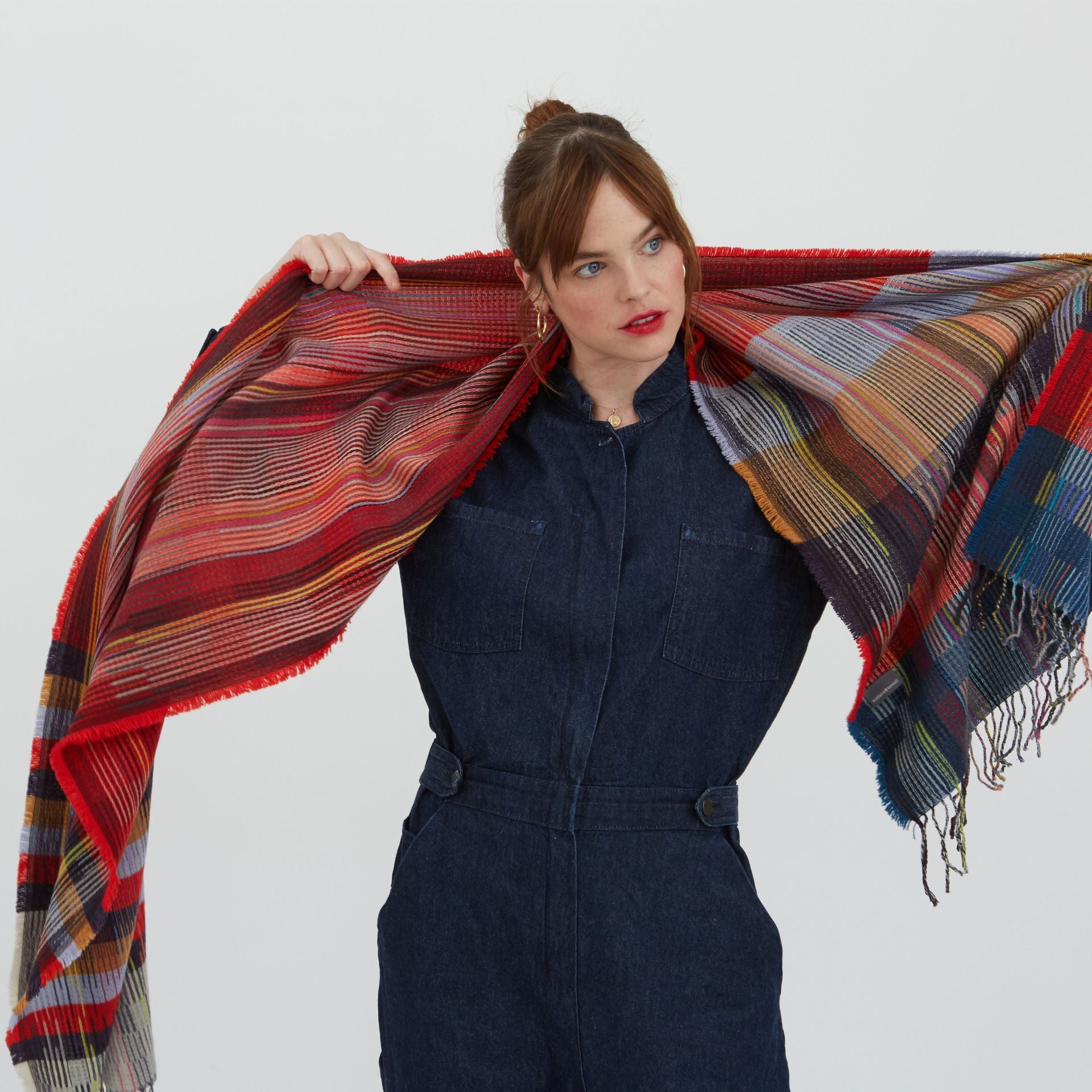 Multicolored striped and plaid wool scarf with fringed edges.  Predominantly red, with blue, brown, and yellow accents.