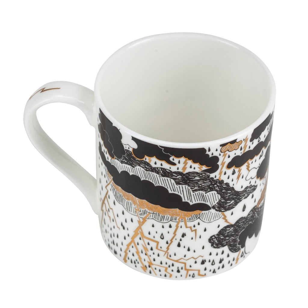 White mug with black and gold illustration of a stormy weather scene featuring clouds, lightning, and rain.