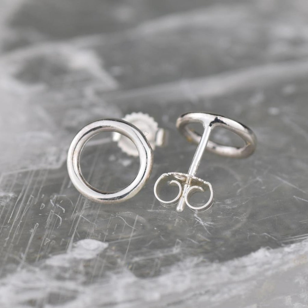 Pair of silver circle stud earrings.  One earring shows the post and butterfly clasp.