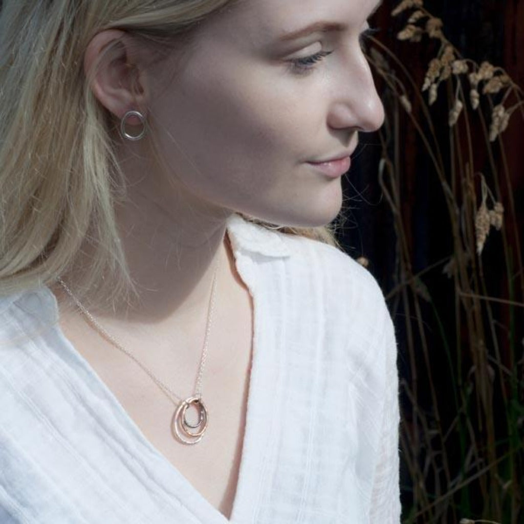 Silver necklace featuring three interlocking circles in silver, rose gold, and dark metal.