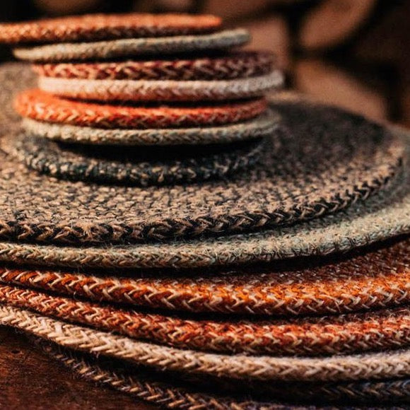 A loosely arrange pile of jute coasters by British Standard, in a variety of colours and sizes.