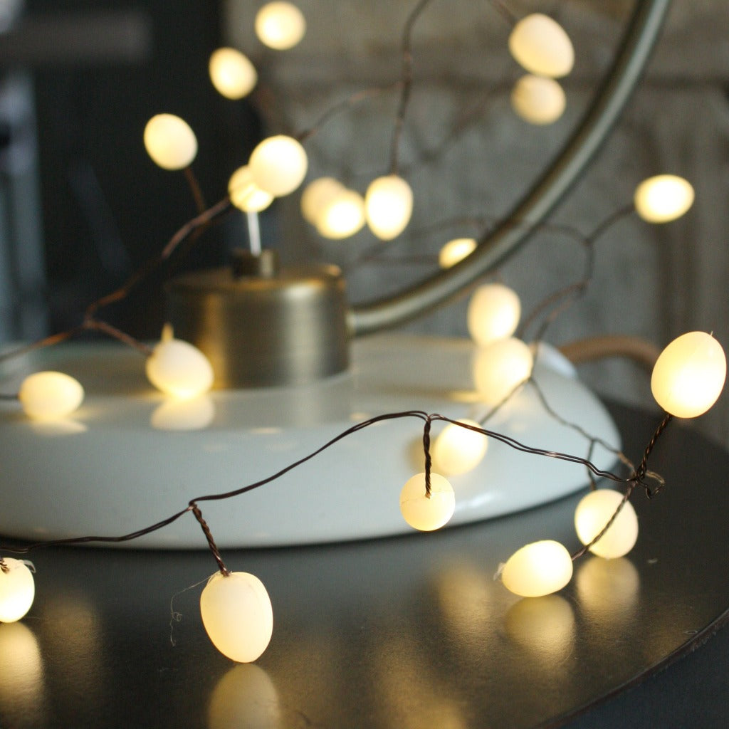 String of warm-white LED lights with round, opaque bulbs on a brown wire.