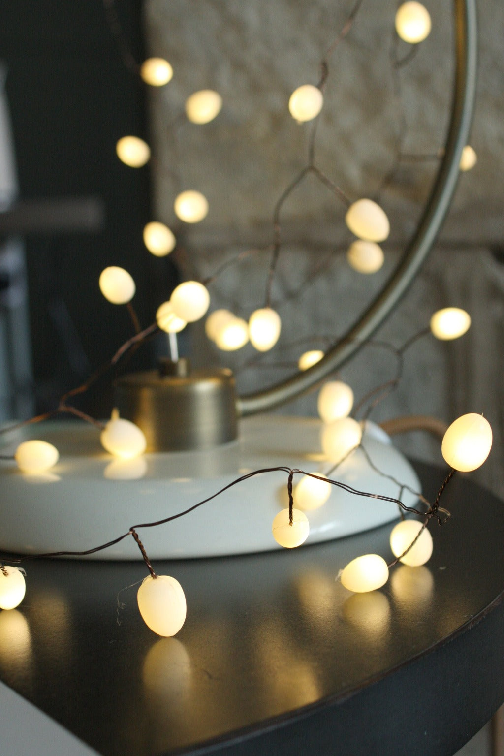 Warm-white LED string lights with round bulbs, draped over a table lamp base.