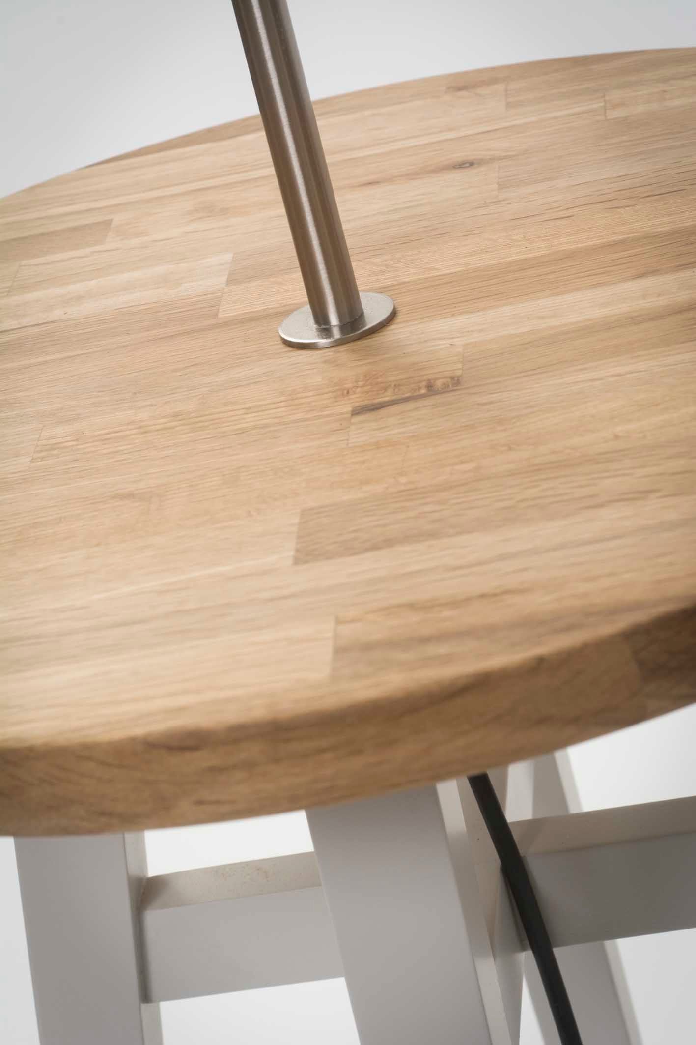 Round wooden table top with a stainless steel lamp post attached.  The table has a light grey, A-frame base.