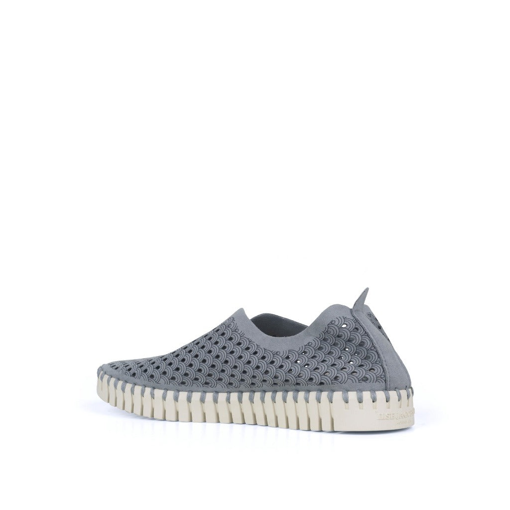 Gray slip-on shoe with patterned cutouts and a cream-colored, textured sole. The design features a repeating wave motif.