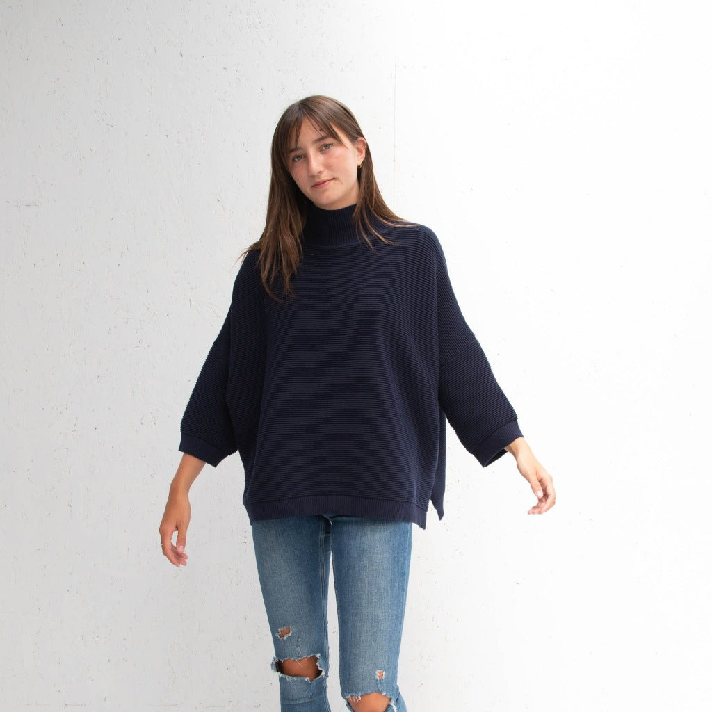 Navy blue ribbed knit turtleneck sweater with three-quarter sleeves and a relaxed fit.